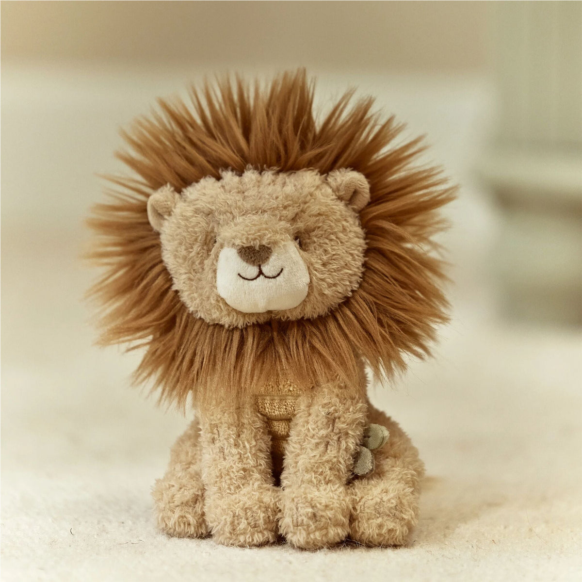 Plush lion toy with a soft texture on a beige background