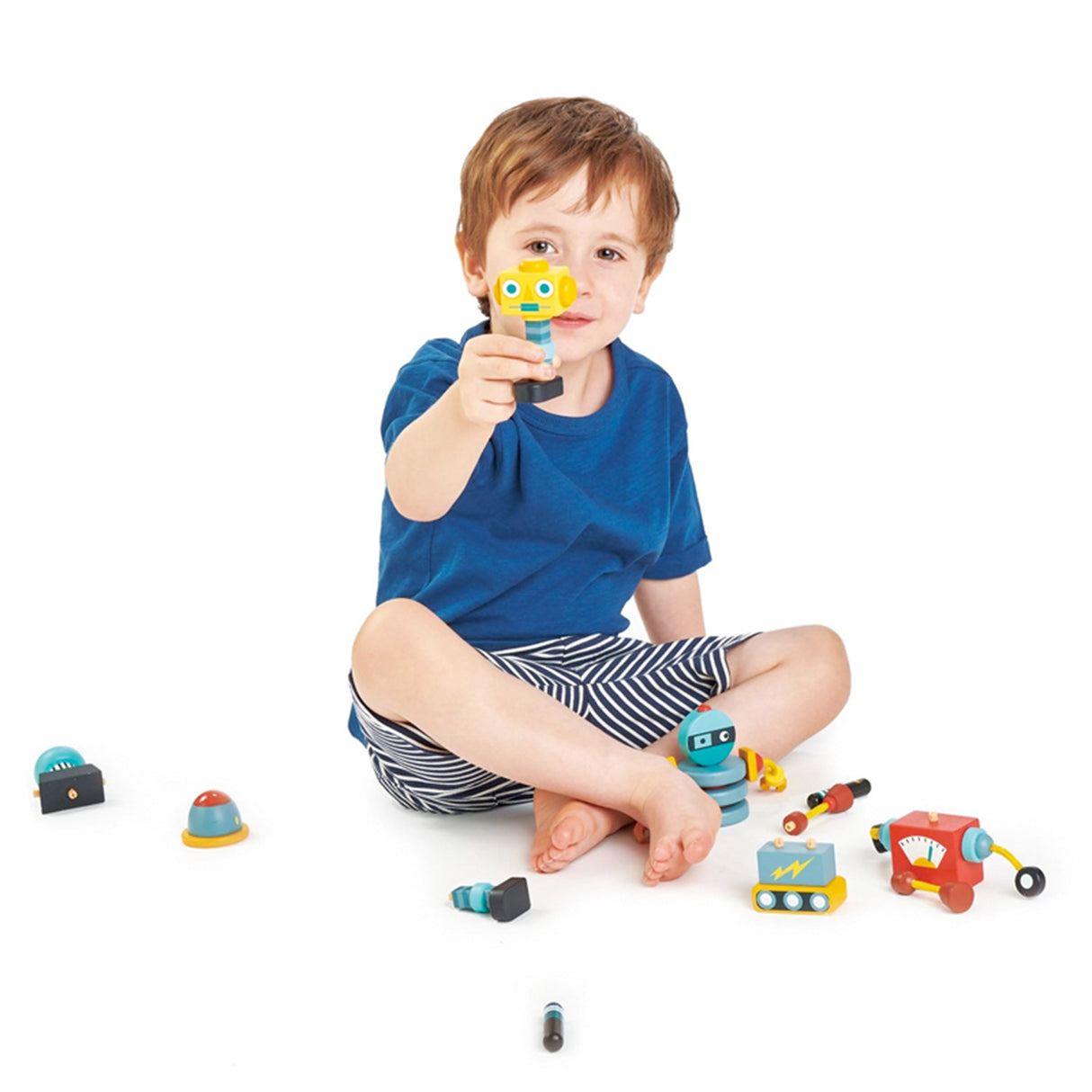 Child playing with wooden toy robots on a white background