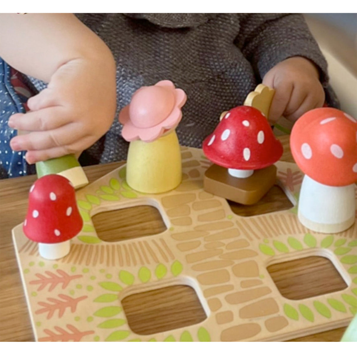Children playing with a wooden mushroom puzzle on a table.