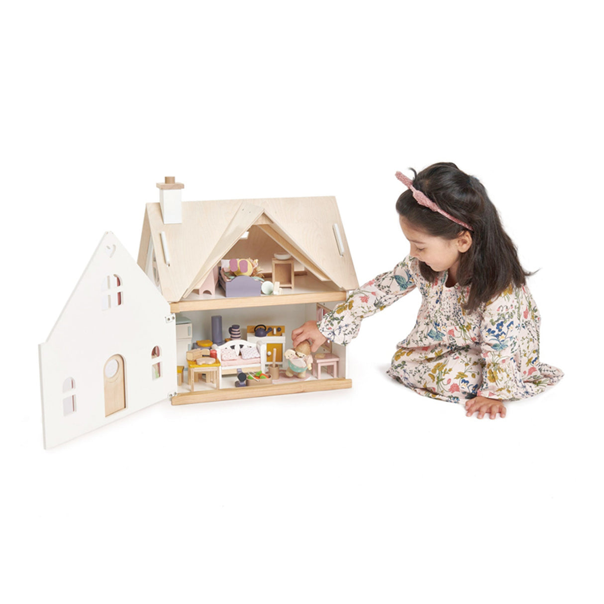 Child playing with a wooden dollhouse on a white background