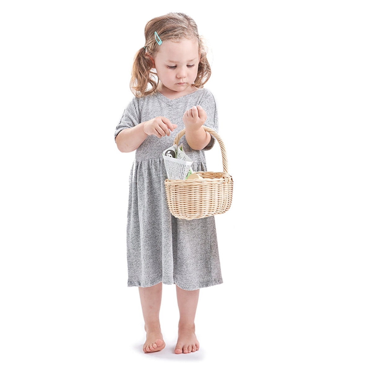 Young girl in a gray dress holding a wicker basket on a white background