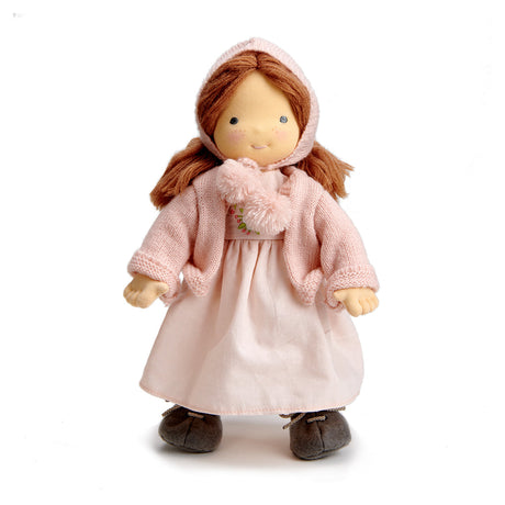 Waldorf style Doll wearing a pink coat, bonnet and dress on a white background