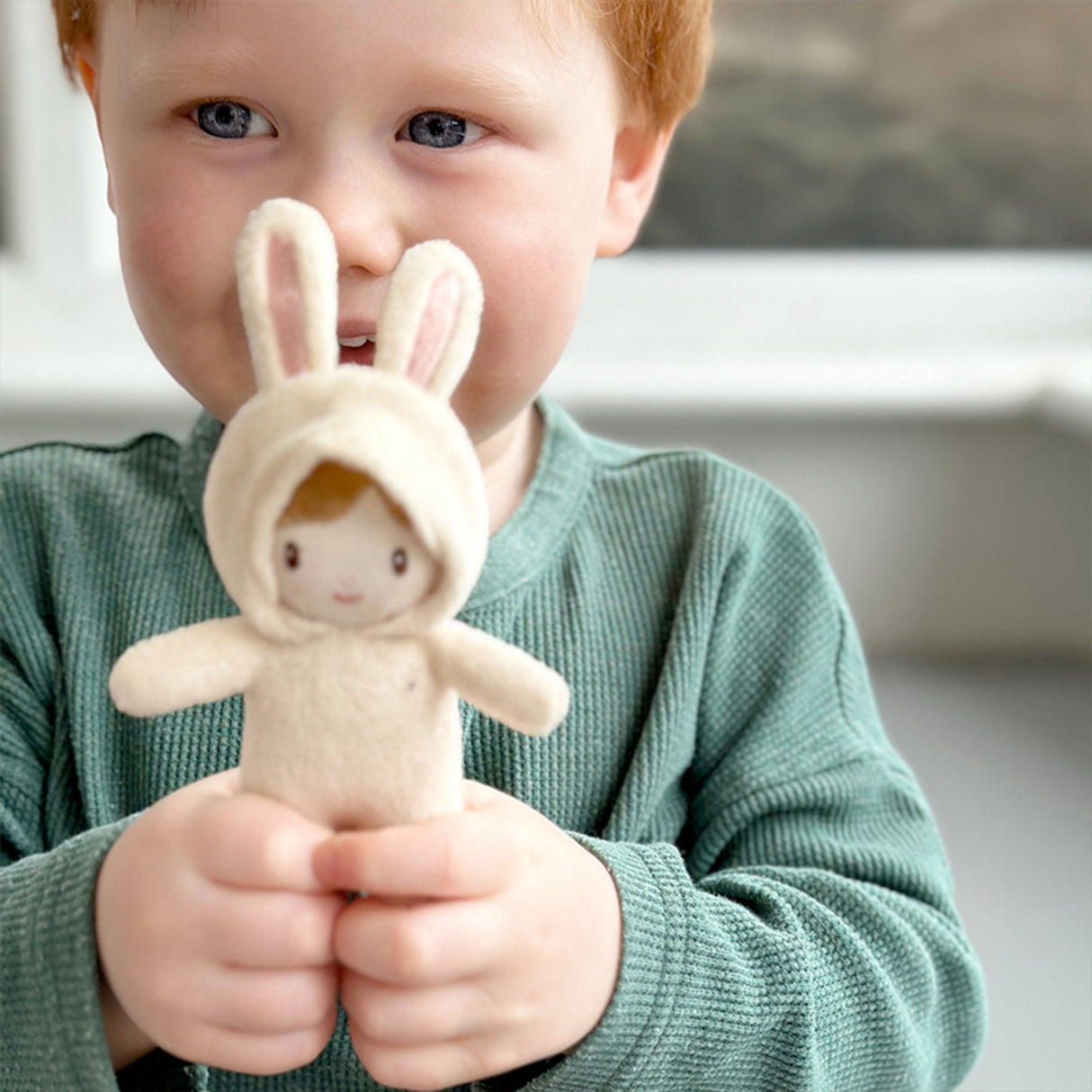 Child holding a plush toy with bunny ears and a face