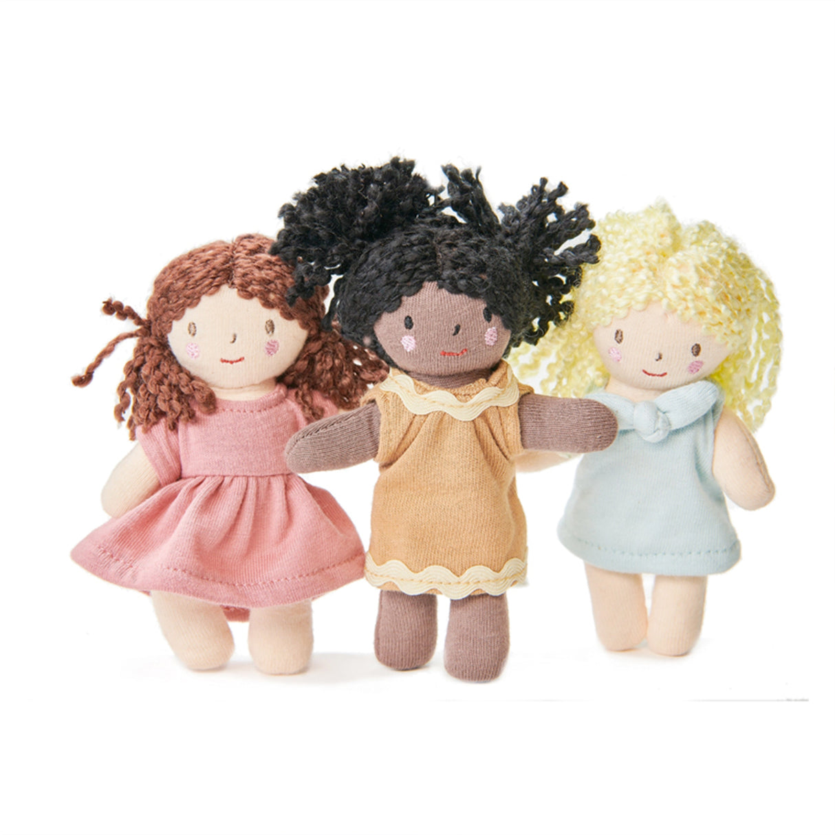 Three dolls with different hair and skin colours and dresses on a white background