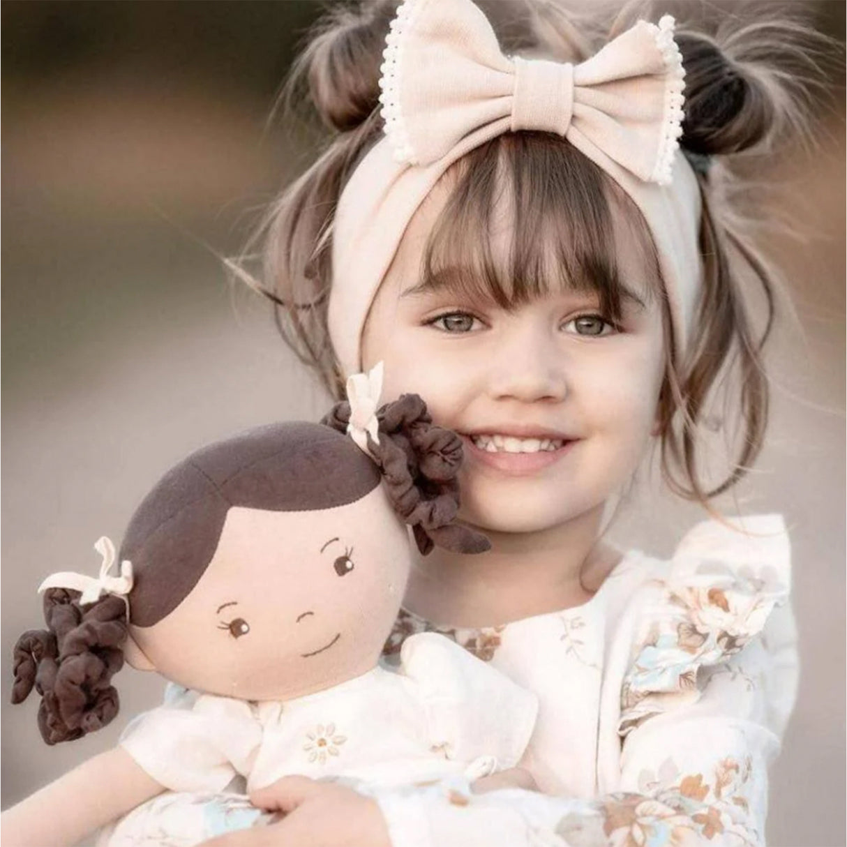 Child holding a rag doll with brown hair on a blurred background