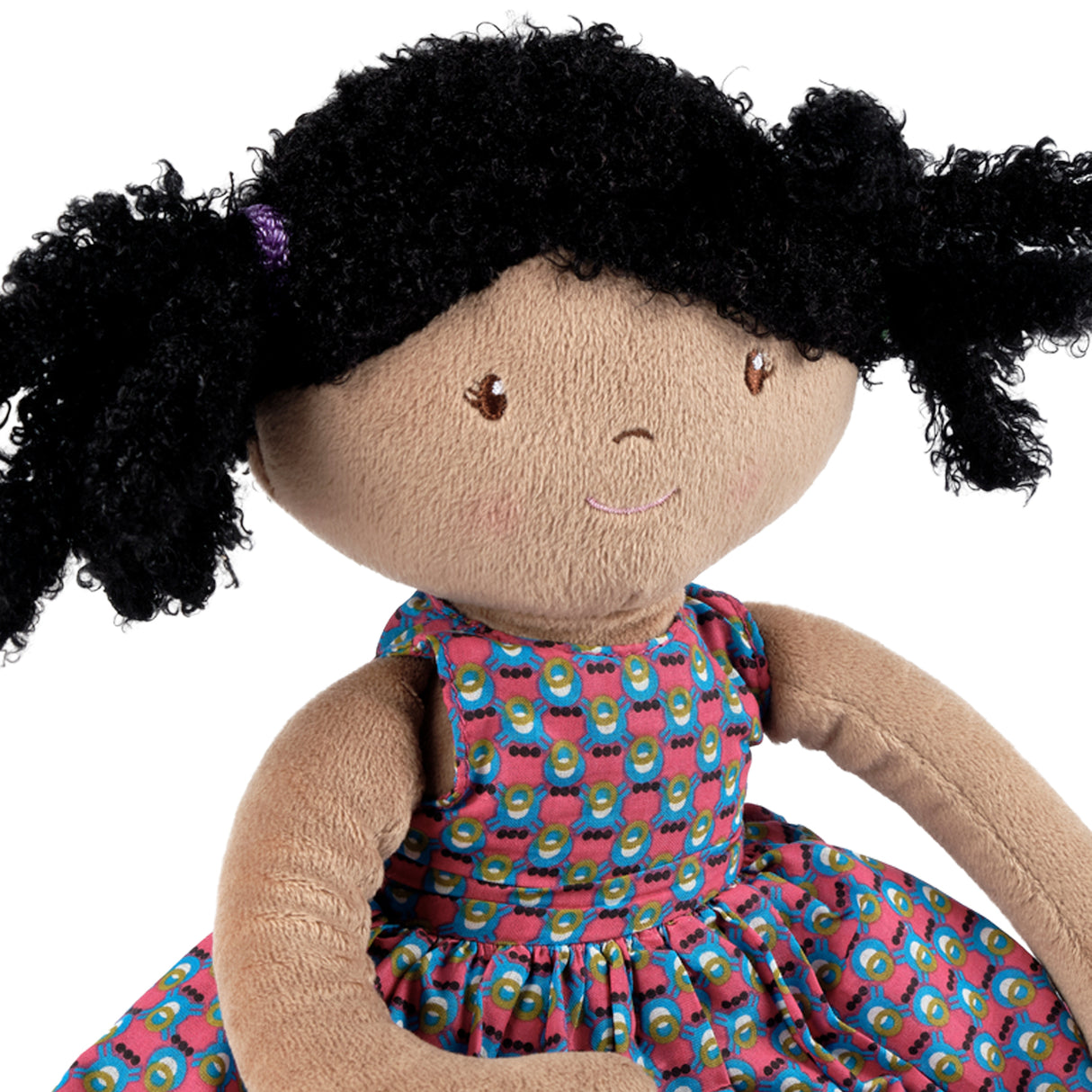 Soft doll with black hair and a colourful dress on a white background