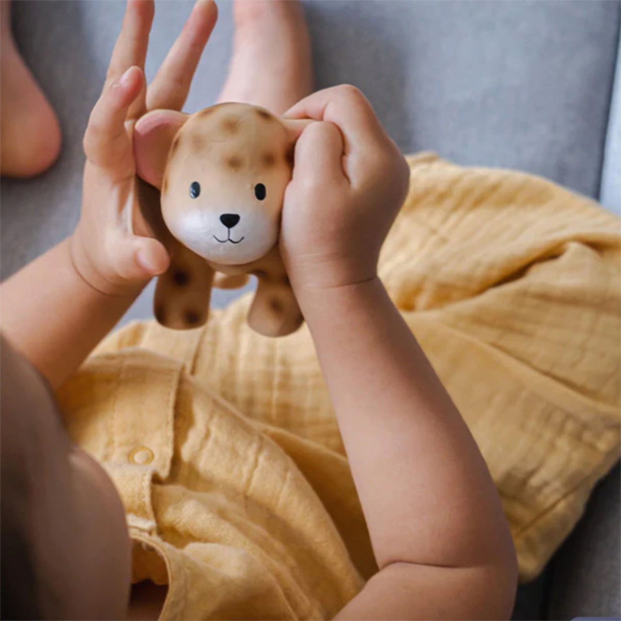 Child holding a rubber leopard toy with a blurred background
