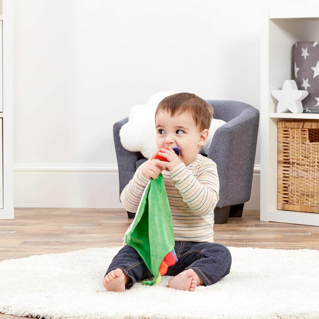 Child playing with The Very Hungry caterpillar Green comfort blanket with colorful rainbow edges and tags.