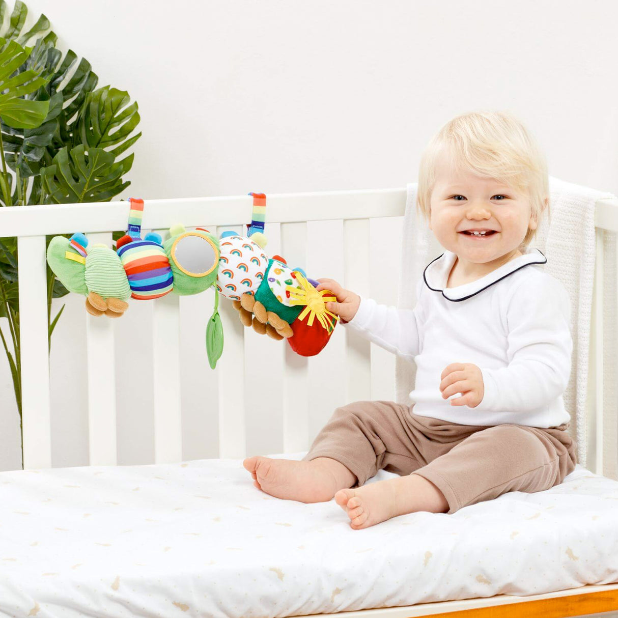 Baby playing with Colorful Very Hungry caterpillar shaped baby toy with various textures and mirrors on a white background