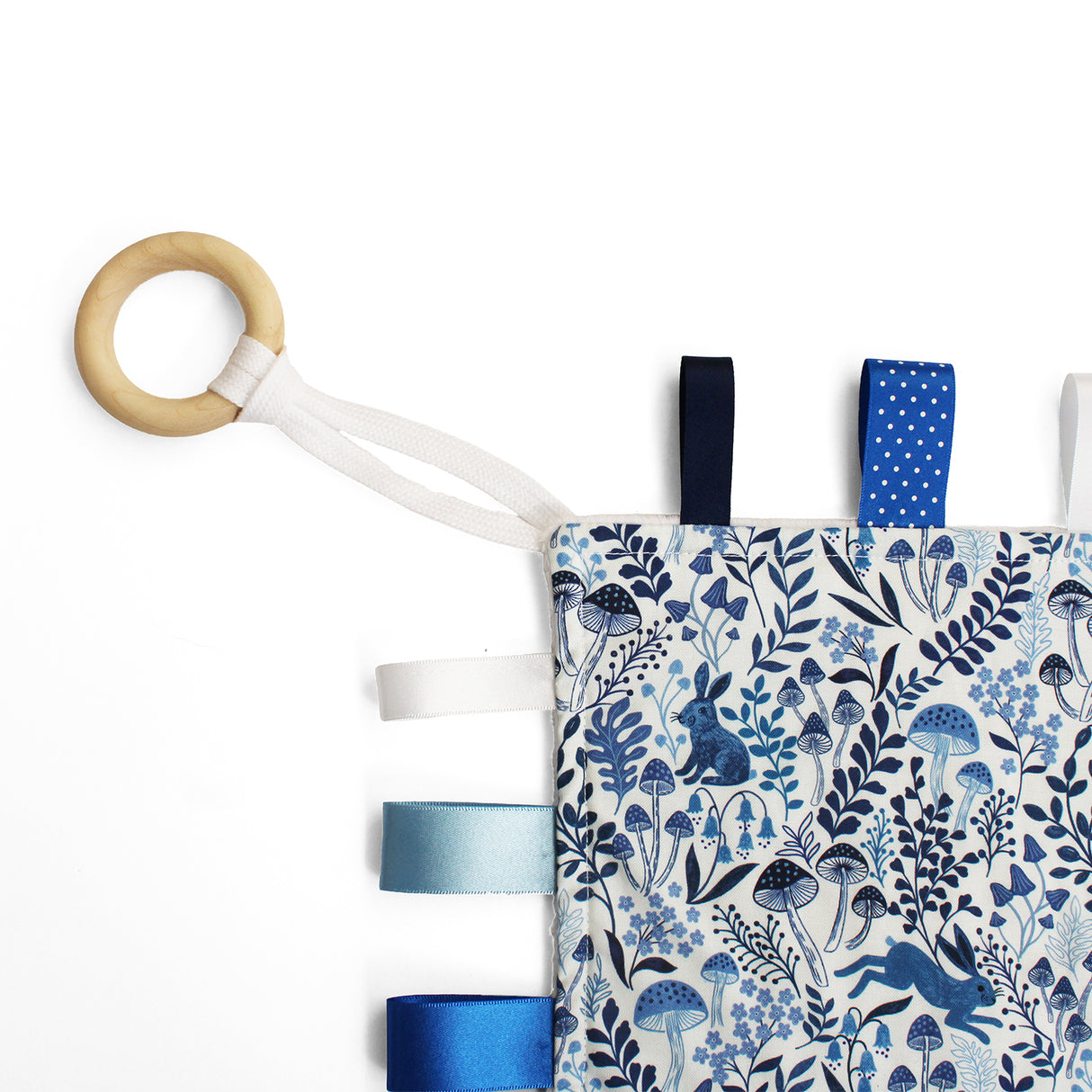 Baby comforter with wooden ring featuring blue animal and plant pattern on a white background
