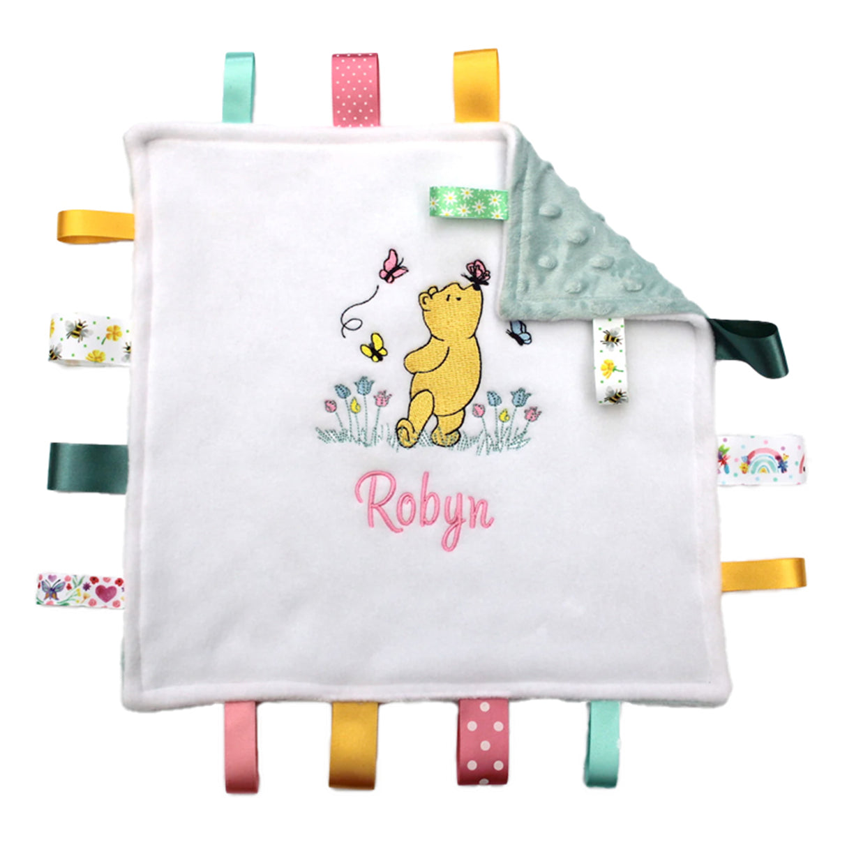 Personalised Winnie the Pooh with butterflies taggy comforter, green minky back, and multiple colorful satin ribbons. Embroidered with the name under design