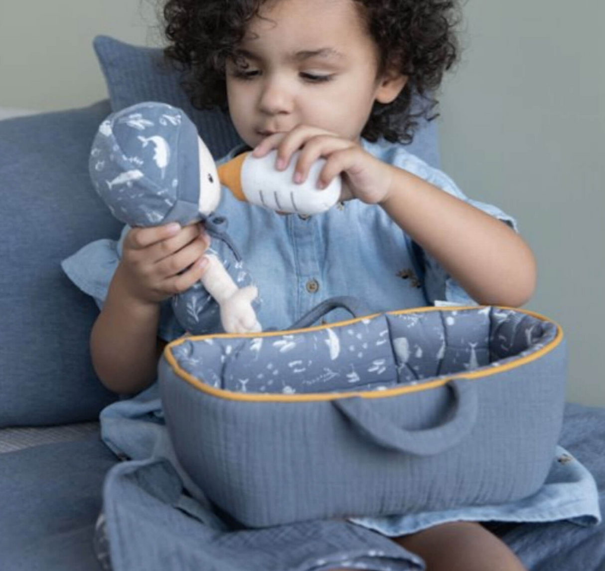 Child playing with Baby Boy Jim and carry cot doll and fabric baby bottle