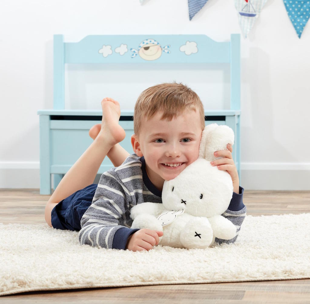 Another front view of Just Miffy an adorable cuddly soft toy based on the classic cute white bunny created by the late Dick Bruna pictured with a smiling happy young boy holding a Classic Miffy