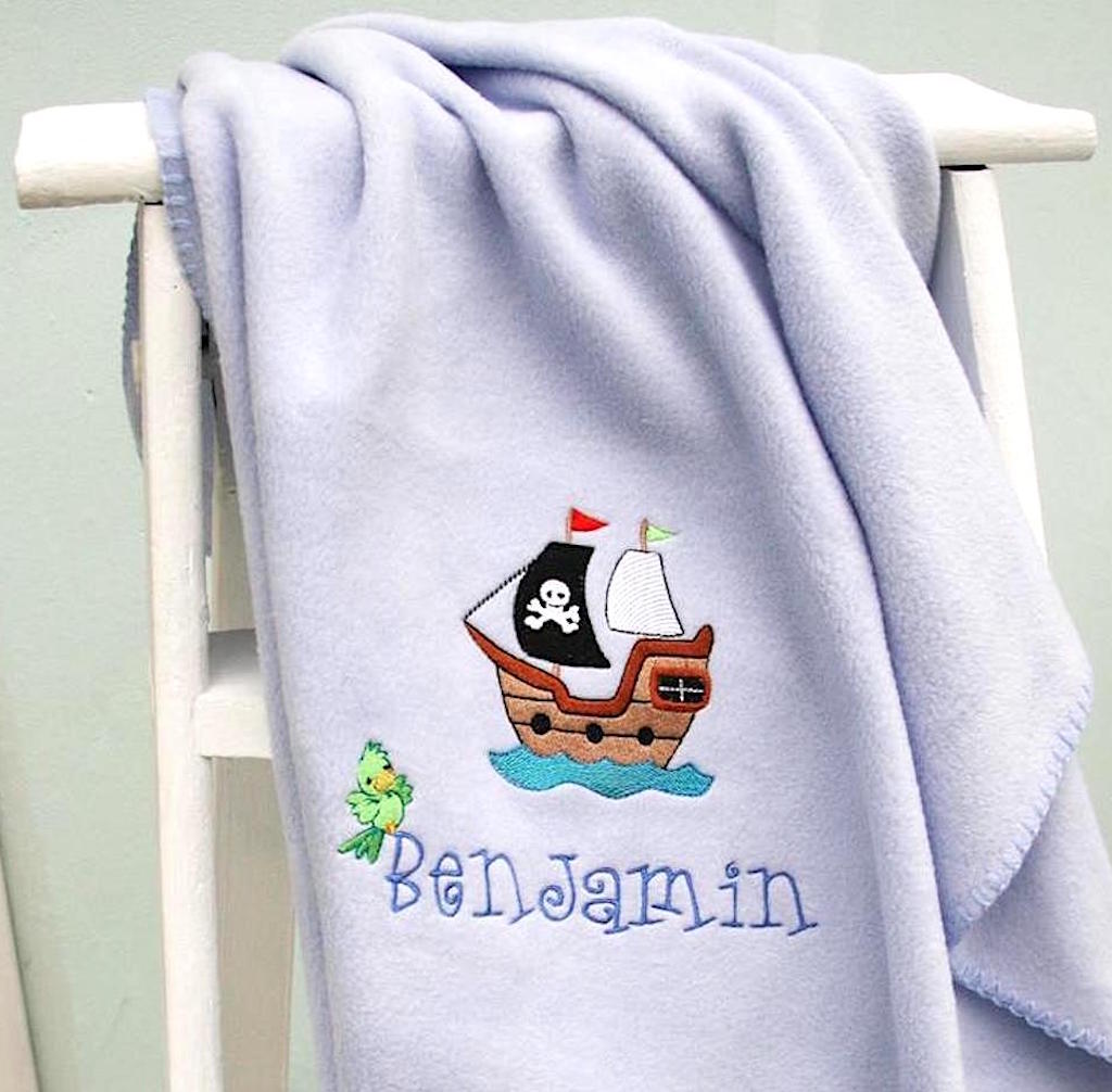 On a white set of steps a Personalised pirate blanket with buccaneer pirate's ship on blue blanket