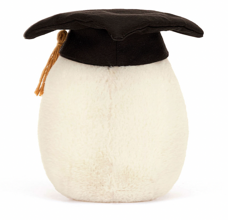 A plush toy resembling a boiled egg wearing a black graduation cap with a golden tassel.