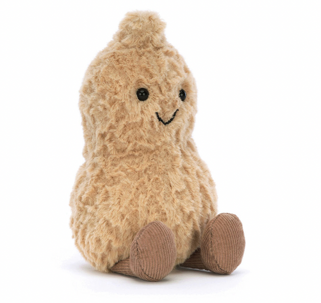 A soft plush toy resembling a peanut with a beige tumbly-textured shell, chocolate boots, and a tuft on top of its head.