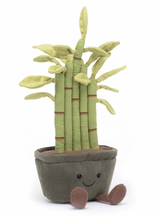 A plush toy resembling a potted bamboo plant with green leaves, red-brown stitch details, and a gray pot. The toy has a cheerful expression and fluffy soil at the bottom.