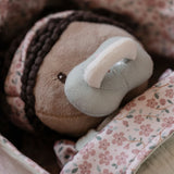 Close up of Little Dutch Baby Doll Evi face with magnetic dummy attached, nestled in floral-lined basket