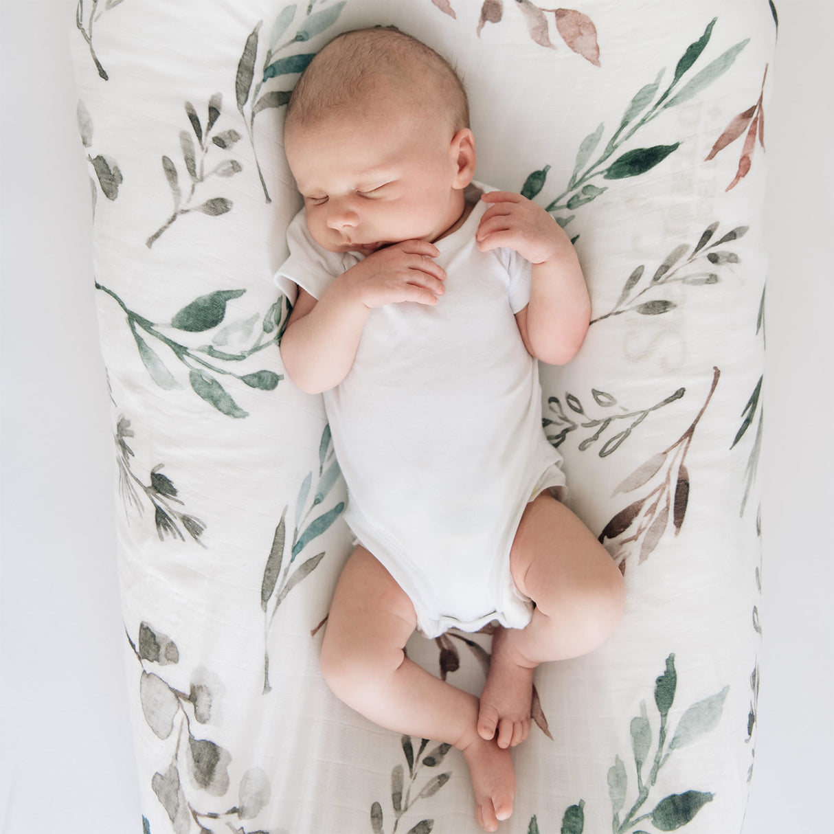 Newborn baby sleeping on a botanical patterned blanket