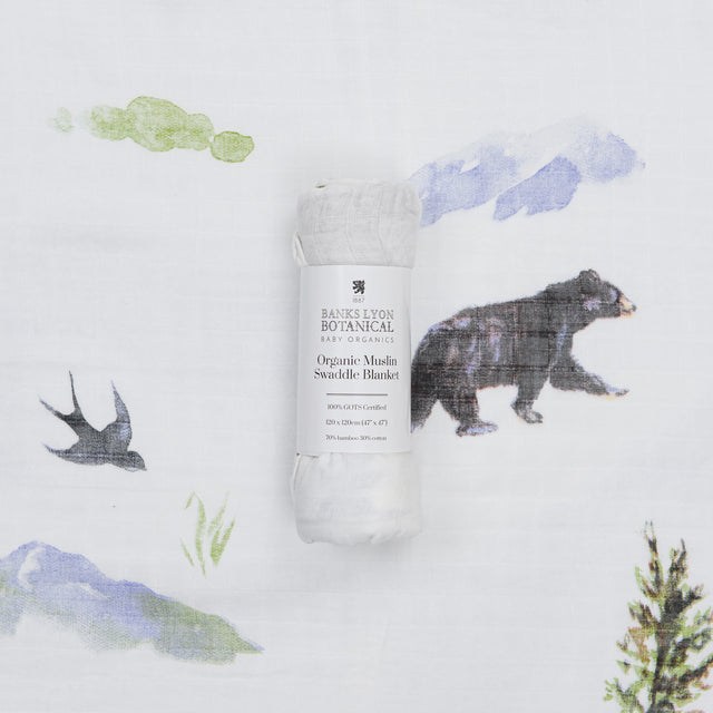 Organic muslin swaddle blanket with nature-themed design on a white background