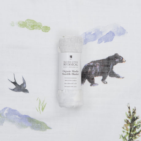 Organic muslin swaddle blanket with nature-themed design on a white background