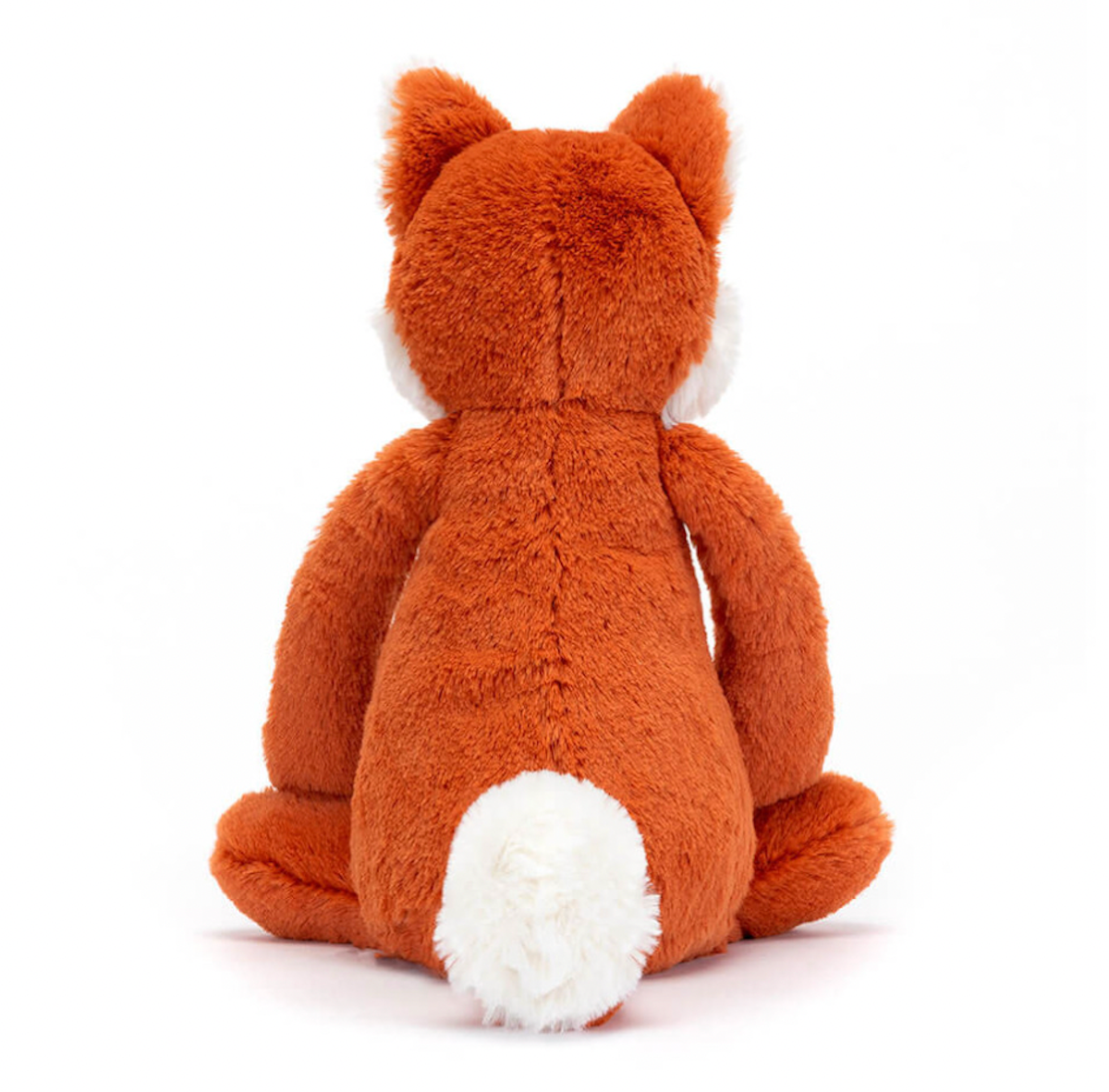 A plush toy depicting a fox cub with fluffy ears, and tail-tip, sitting with a reddish-brown body.