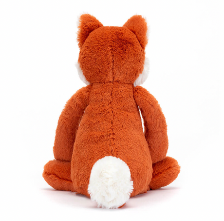 A plush toy depicting a fox cub with fluffy ears, and tail-tip, sitting with a reddish-brown body.