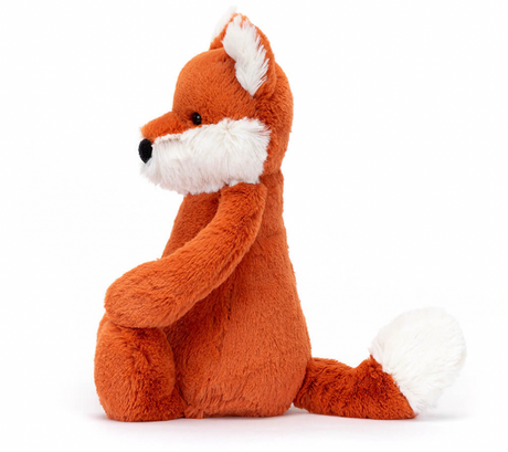 A plush toy depicting a fox cub with fluffy white ears, feet, and tail-tip, sitting with a reddish-brown body.