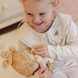 A young blonde girl smiling while holding soft rag doll baby Julia