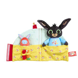A folded out sleep toy featuring a black bunny character in a blue shirt peeking out from a yellow bed, alongside a red bunny figure.