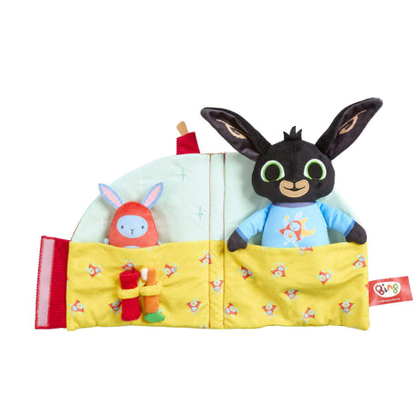 A folded out sleep toy featuring a black bunny character in a blue shirt peeking out from a yellow bed, alongside a red bunny figure.