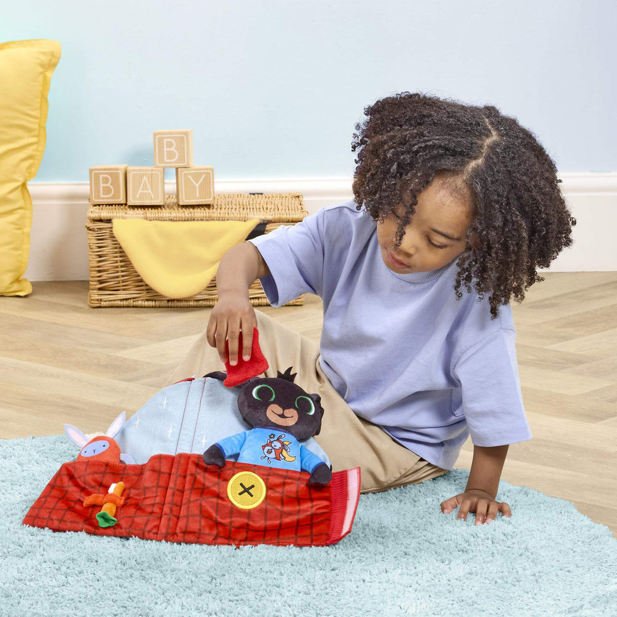 A young child sits playing with Bing Travel Bedtime House