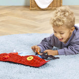 A young child lies on a rug, playing with a bing soft toy 