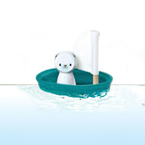 Toy polar bear in a teal boat with a white background