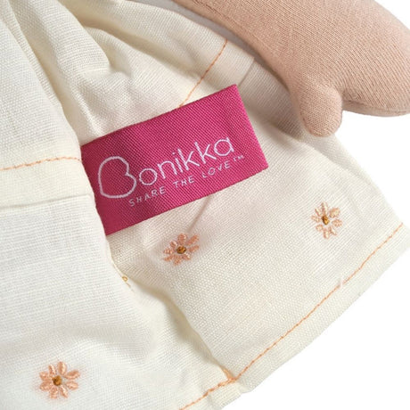 Close-up of a pink 'Bonikka' label on a white fabric with floral embroidery.
