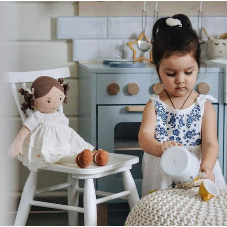 Child playing with a doll in a playroom kitchen setting