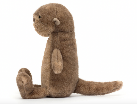 A plush toy depicting a brown otter with a soft, mottled fudge fur texture, butterscotch ears, a black nose, and bright black eyes. It is seated with a long, chunky tail extended.