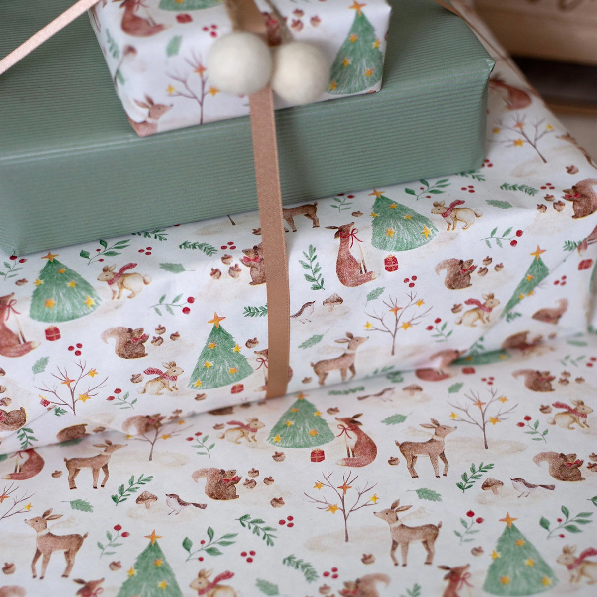 Woodland-themed gift wrap with deer, trees, and other elements on a white background.