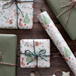 Gift boxes wrapped in festive paper with Christmas designs on a wooden surface.