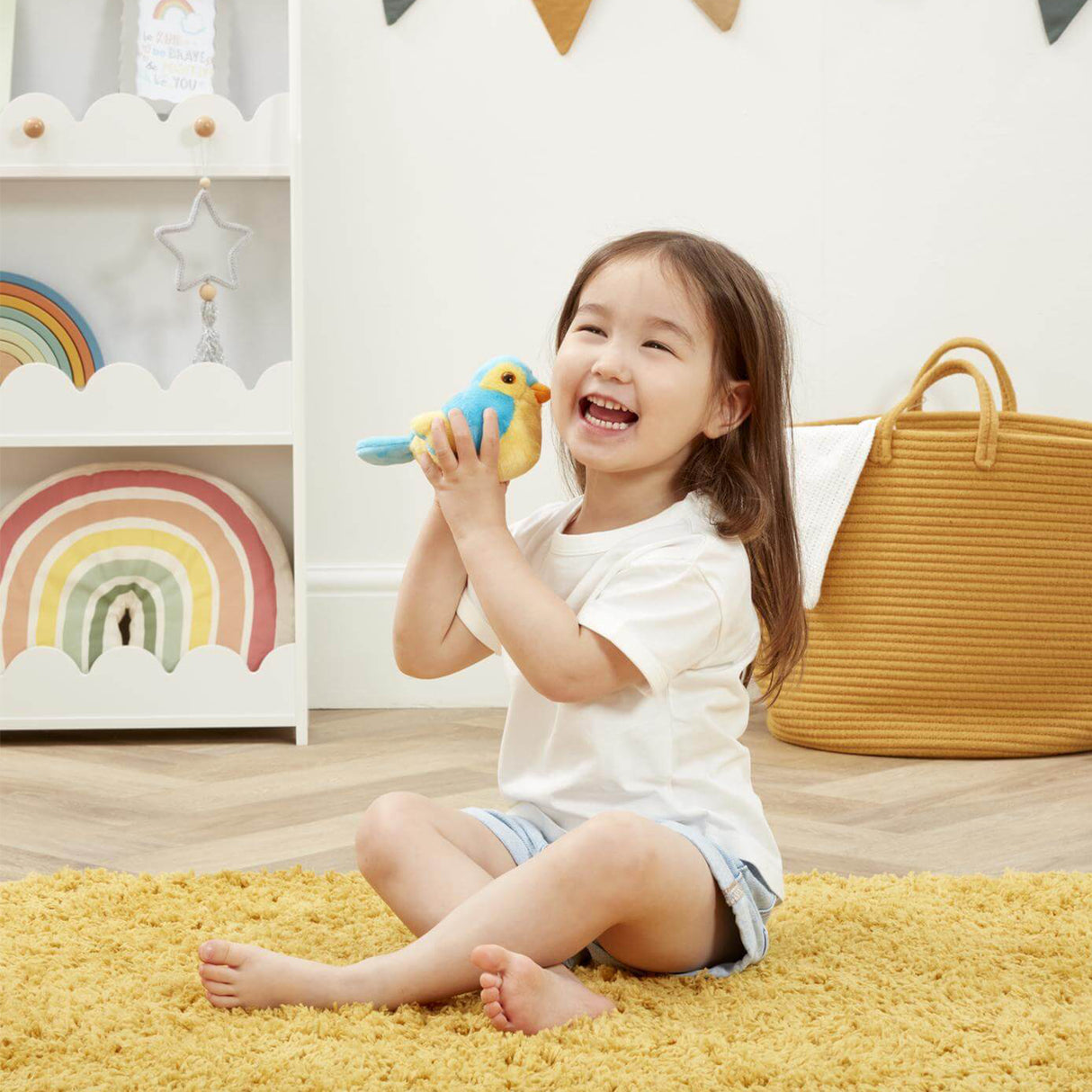 Child playing with a toy in a room with a yellow rug and rainbow decorations.