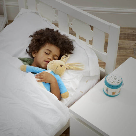 child sleeping with Peter Rabbit soft toy with a musical night light on the side