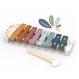A wooden xylophone toy with eight colourful metal bars in orange, brown, pink, gray, blue, and green, accompanied by a wooden mallet, shown on a white background with a decorative leaf graphic.