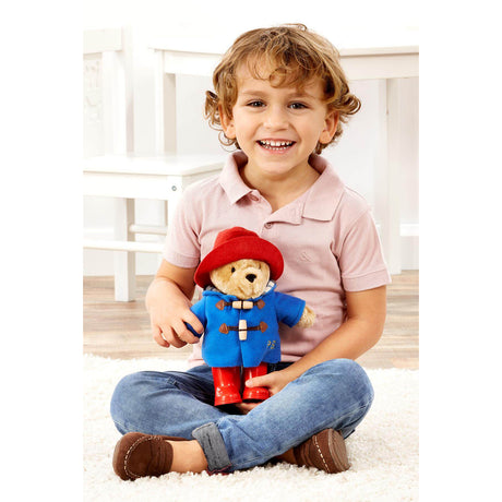 Child holding a Paddington Bear toy in a bright room