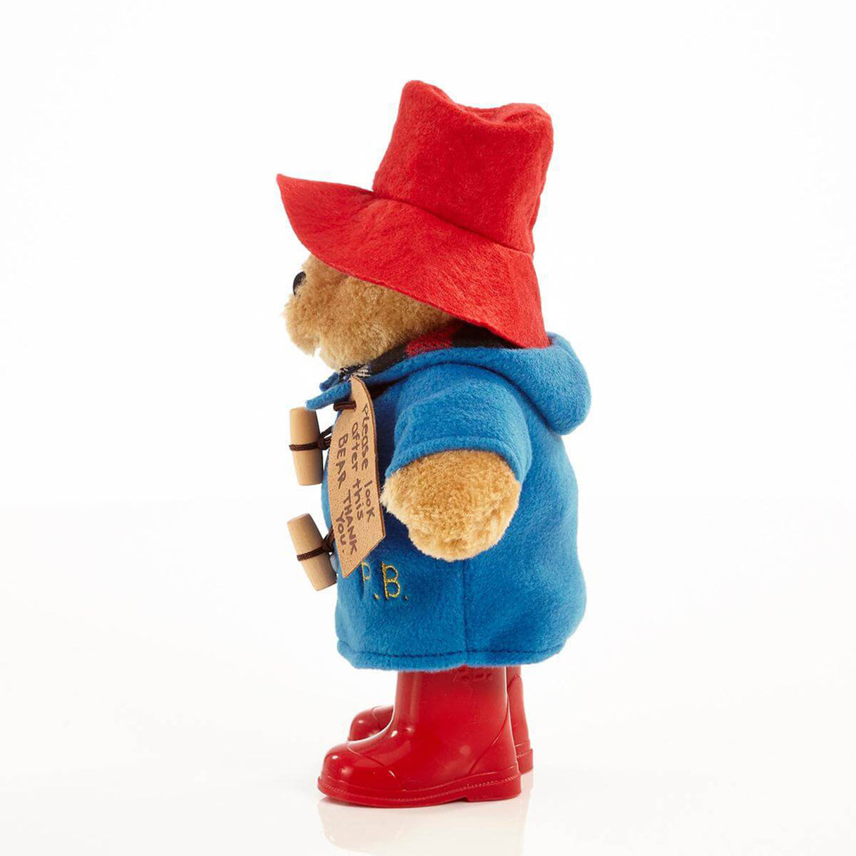 Plush toy bear in a blue coat, red hat, and boots on a white background
