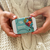 Hands holding a mini beast bracelet kit against a knitted background