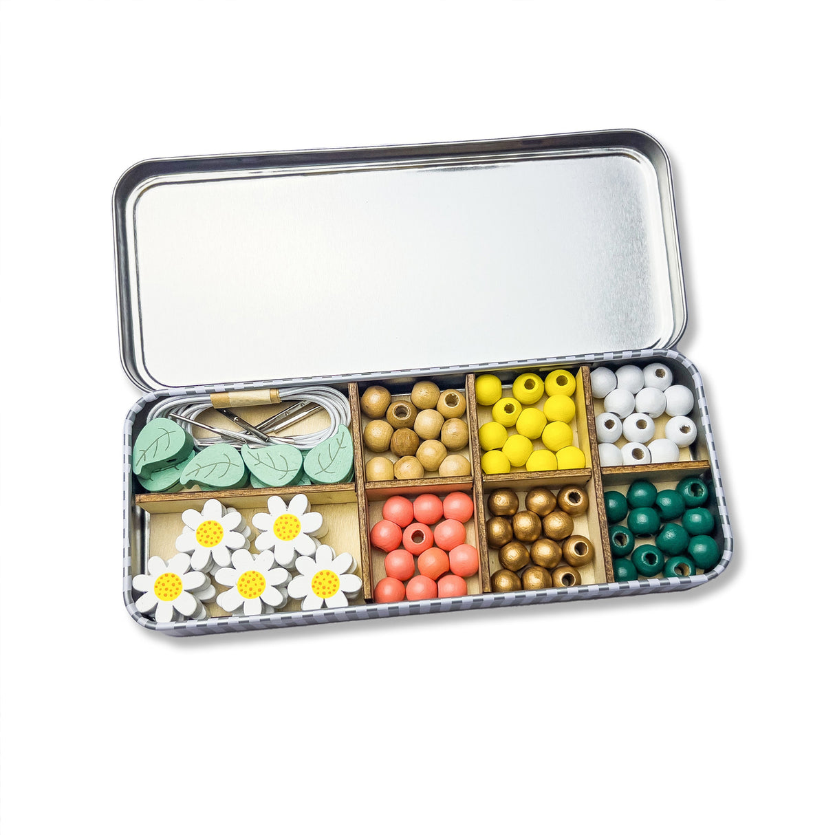 Open tin box with compartments containing colourful beads and flower-shaped items on a white background