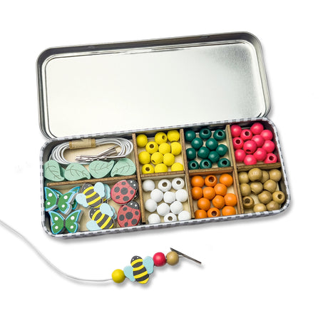 Cotton Twist open tin box with compartments containing colourful beads and decorative items on a white background