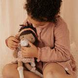 Little girl playing with her soft doll and a cup