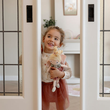Young girl smiling and holding Little Dutch Fairy Mila doll, lifestyle shot indoors