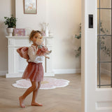 Young girl carrying Little Dutch Fairy Mila doll in a bright living room, lifestyle shot